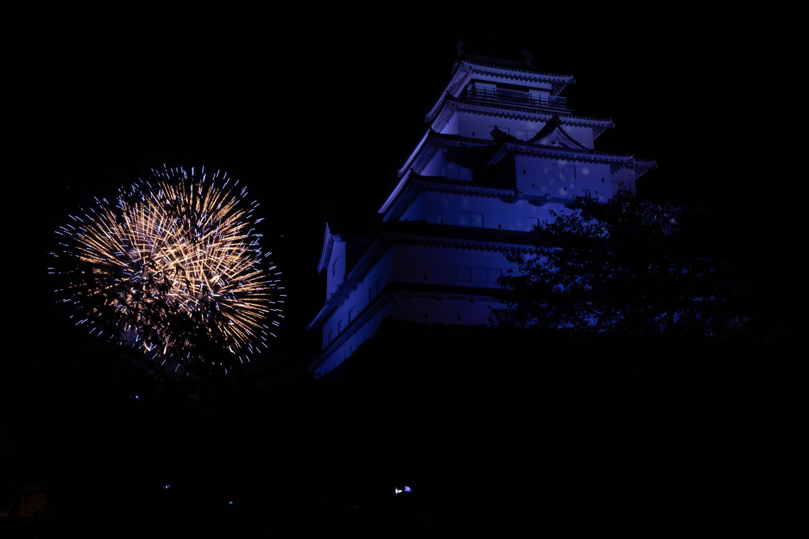 Fireworks beside a Japanese castle at night