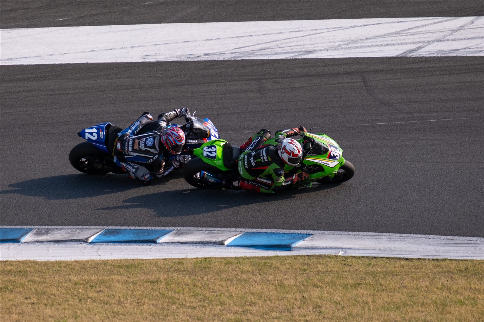 Two motorcycle racers leaning through a corner on track